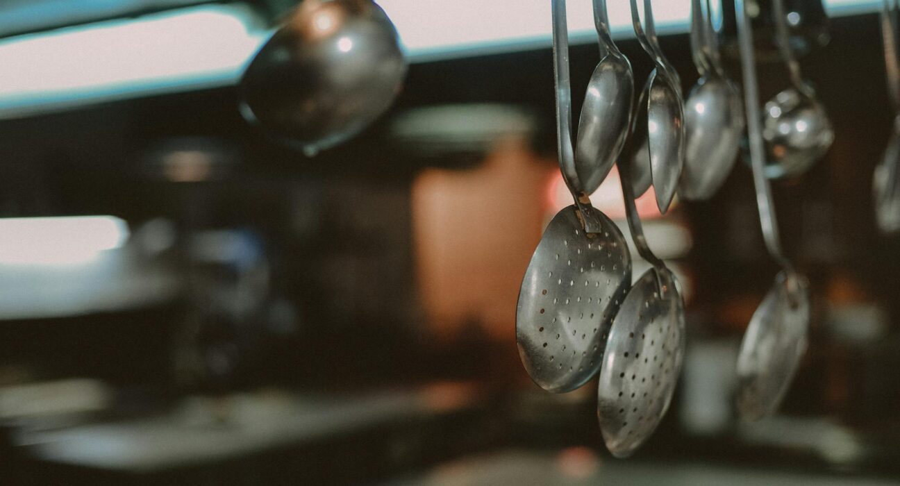 Close-up of hanging metal spoons and ladles in a kitchen, blurred background