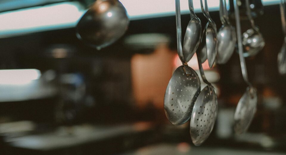 Close-up of hanging metal spoons and ladles in a kitchen, blurred background