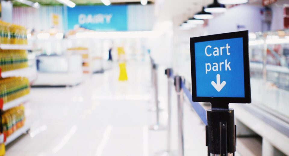 Blue signboard with inscription Cart park placed near counter with products in contemporary supermarket