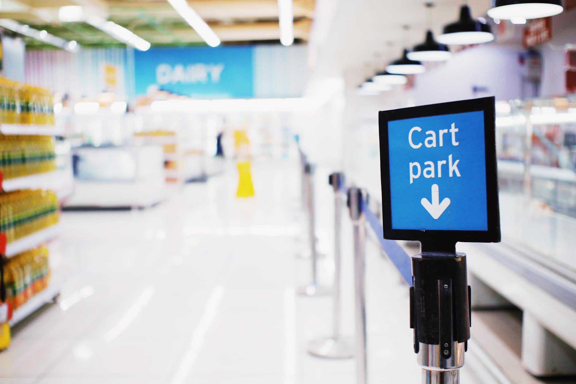 Blue signboard with inscription Cart park placed near counter with products in contemporary supermarket