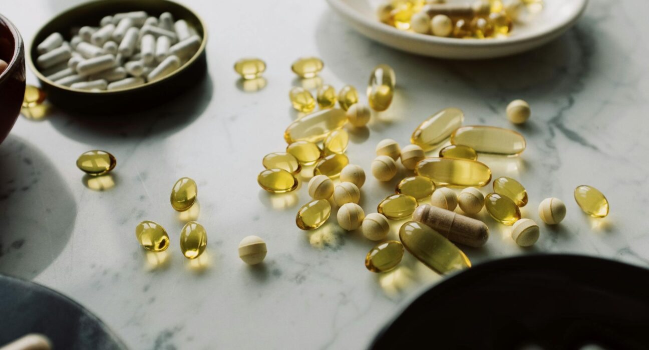 A close-up of assorted pills and supplements arranged on a marble surface, highlighting healthcare and wellness themes.