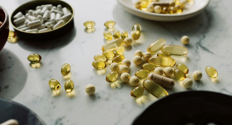 A close-up of assorted pills and supplements arranged on a marble surface, highlighting healthcare and wellness themes.