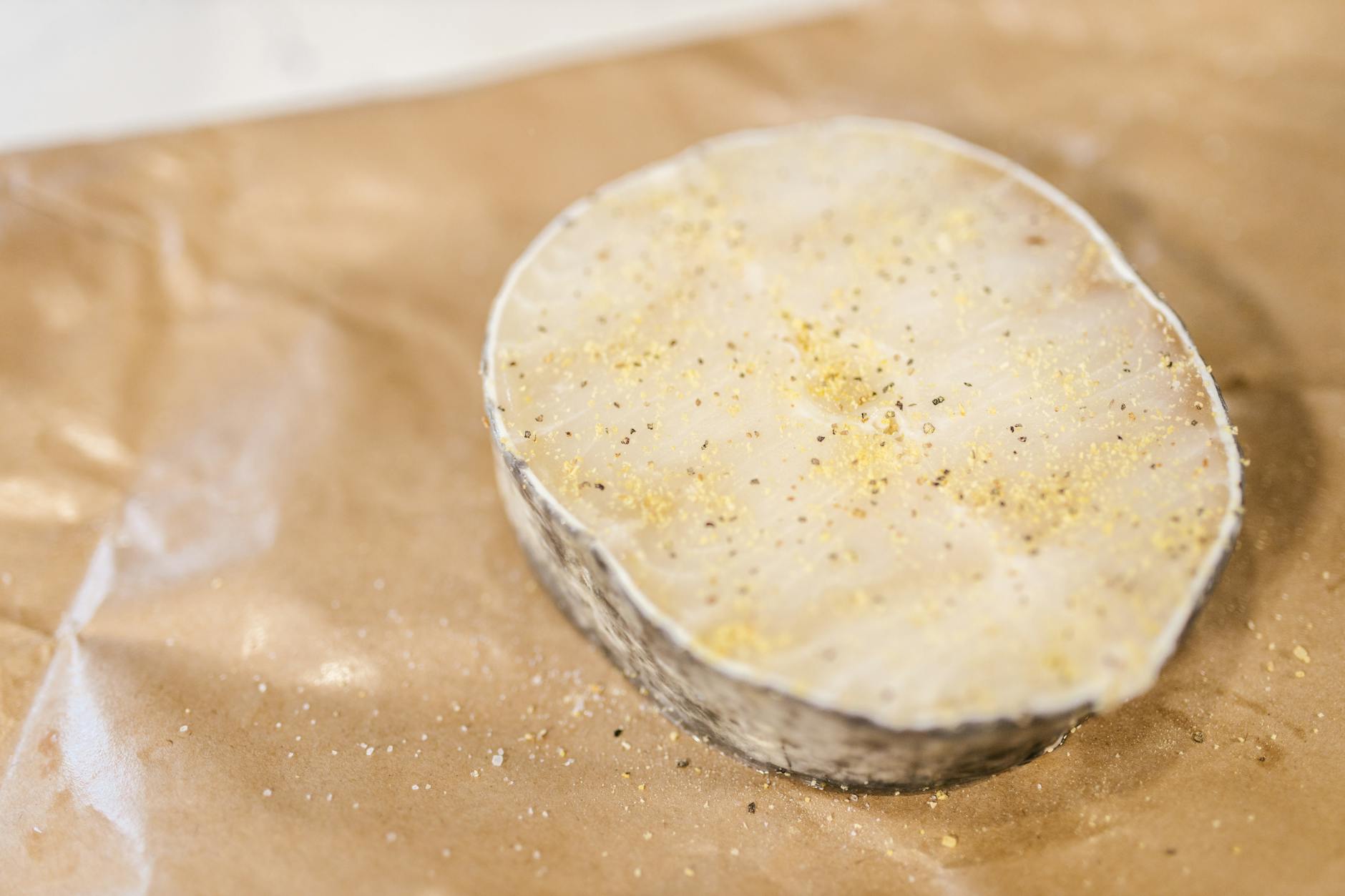 High-quality image of a raw fish fillet with seasoning placed on paper, ready for cooking.