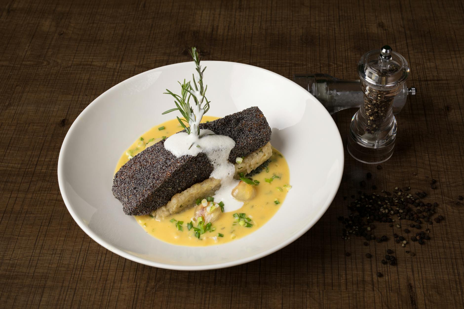 A high-angle shot of popcorn crusted fish with creamy sauce, presented on a wooden table.
