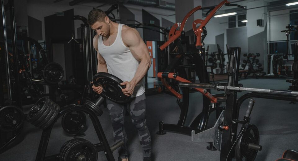 Muscular man lifting weights in a well-equipped gym for strength training.