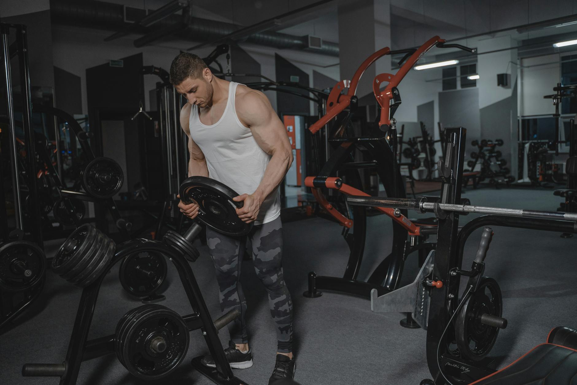 Muscular man lifting weights in a well-equipped gym for strength training.