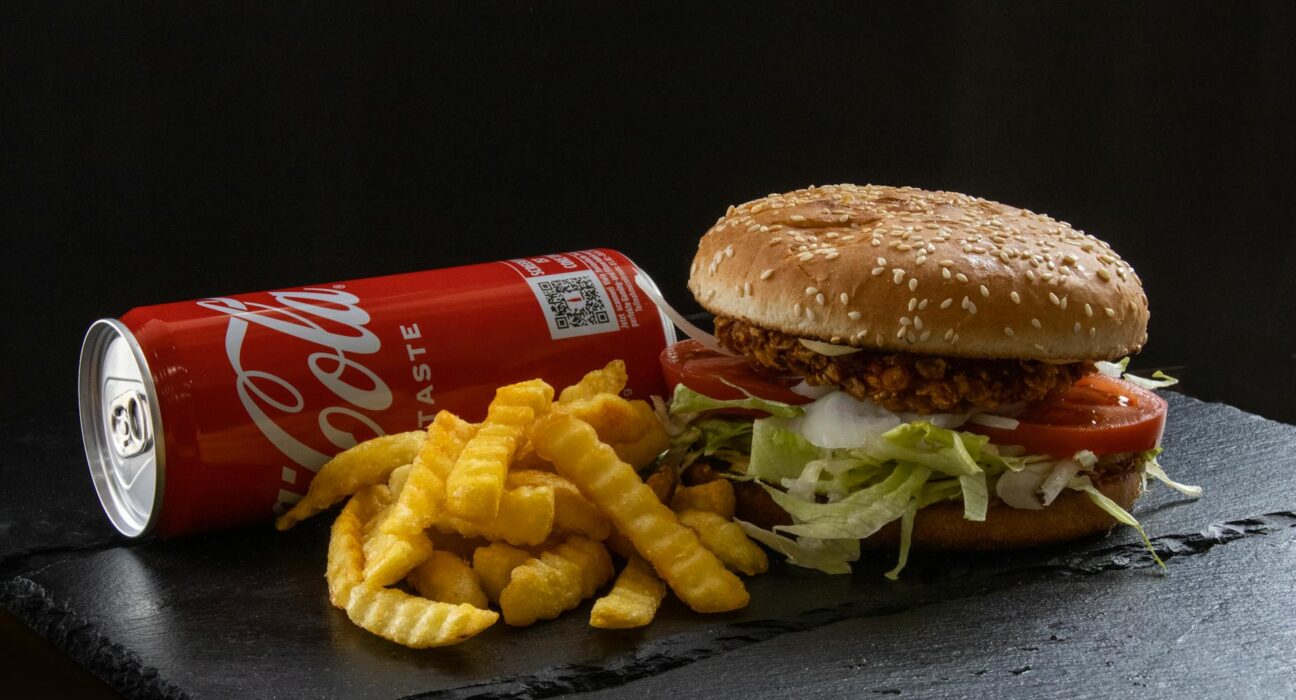 Tasty crispy chicken burger with fresh fries and a soda, perfect for a fast-food craving.