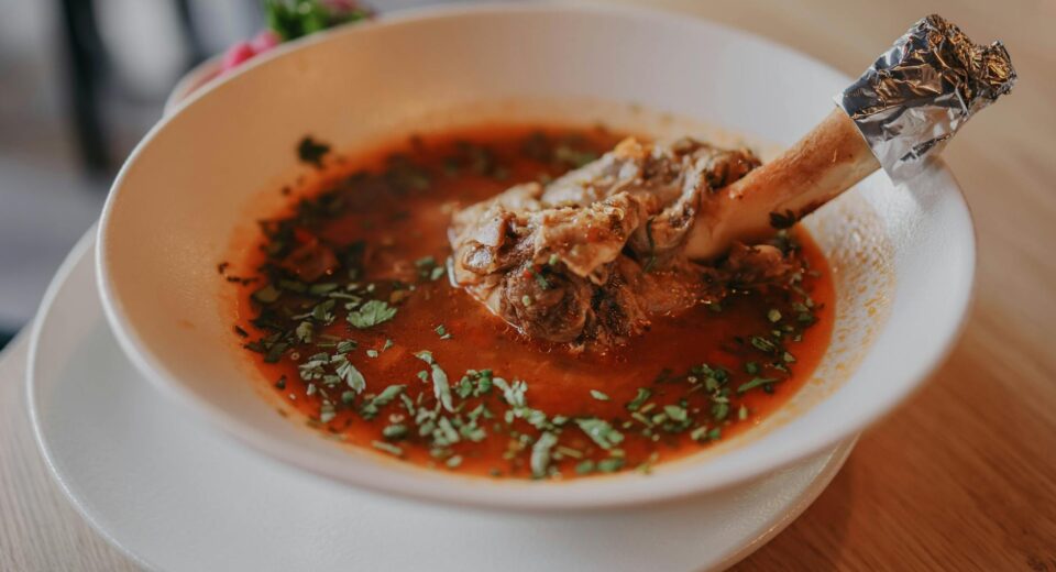 Delicious lamb shank soup garnished with fresh herbs, perfect for a cozy meal.