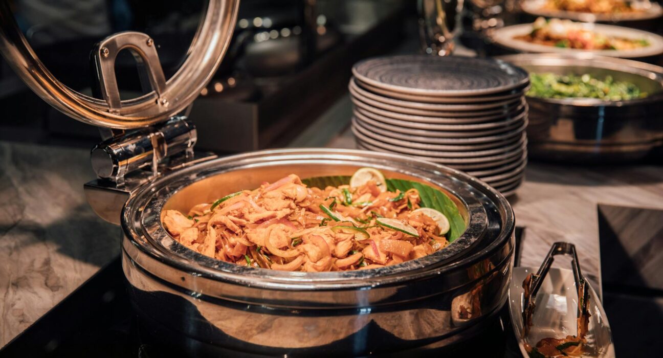Delicious buffet style chicken curry in a chafing dish with lime and veggies.
