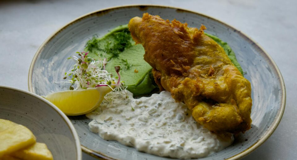 Tasty fish and chips served with tartar sauce and mushy peas.