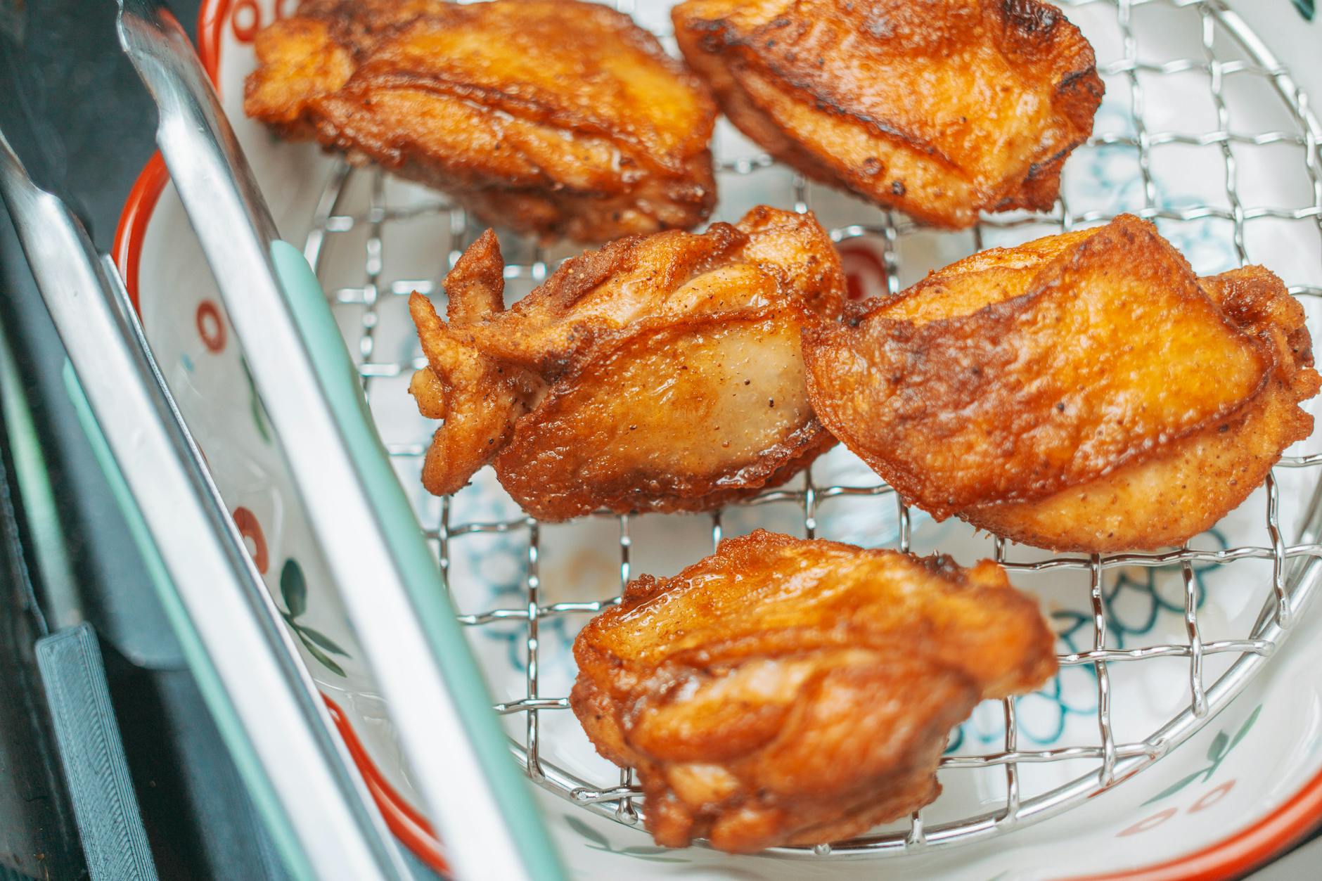 Golden brown fried chicken pieces cooling on a wire rack, perfect for a delicious meal.