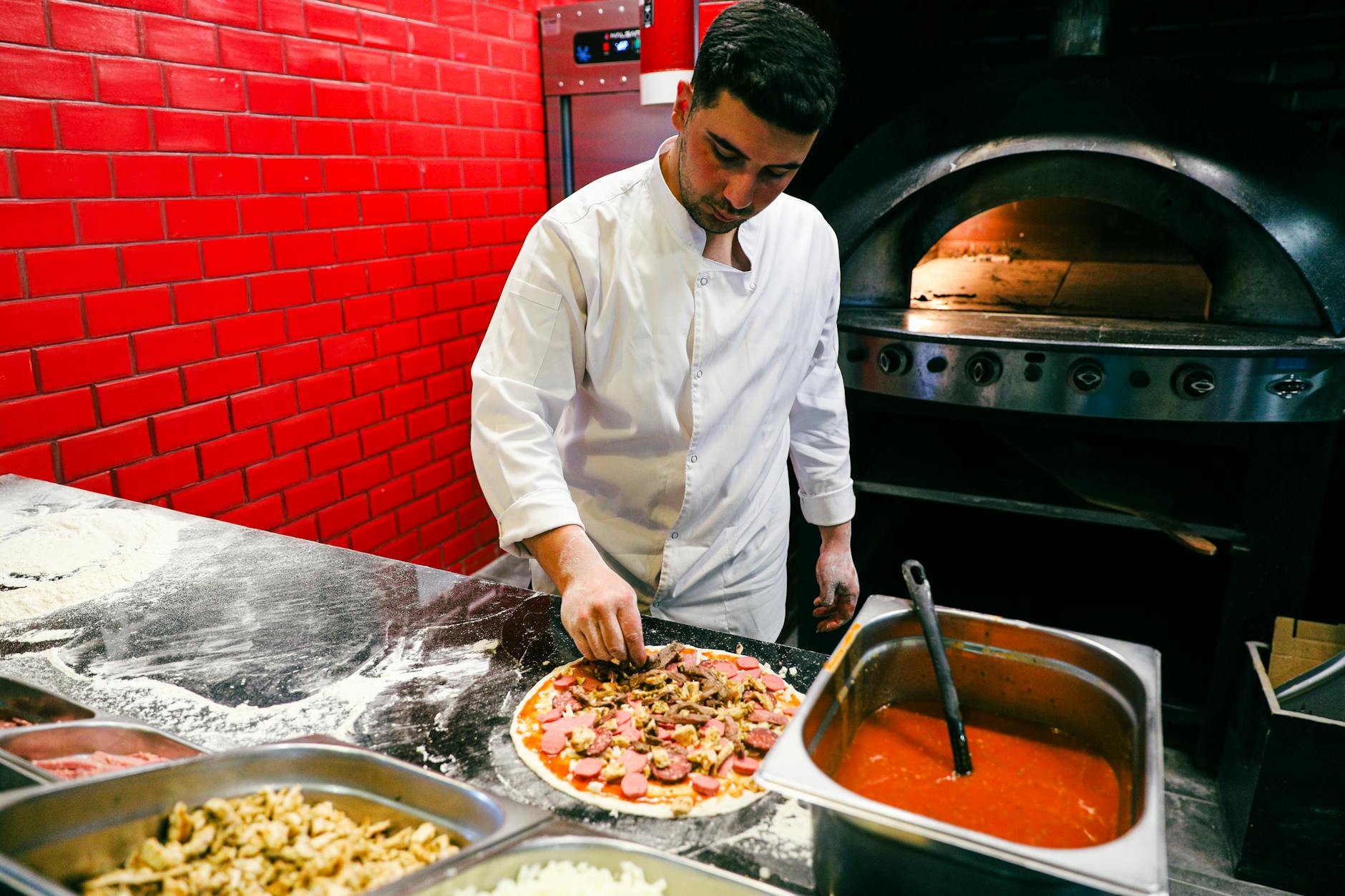 Chef in white uniform preparing pizza in a brick oven kitchen. Italian cuisine and culinary art.