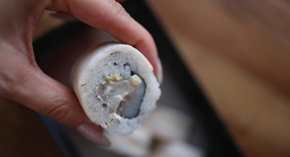 Detailed view of a sushi roll held by hand with soft focus background.