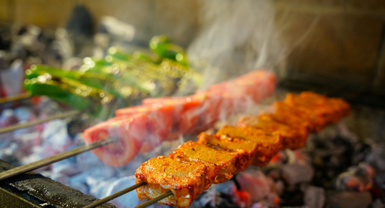 Juicy Turkish kebabs grilling on charcoal, showcasing vibrant spices and fresh vegetables.