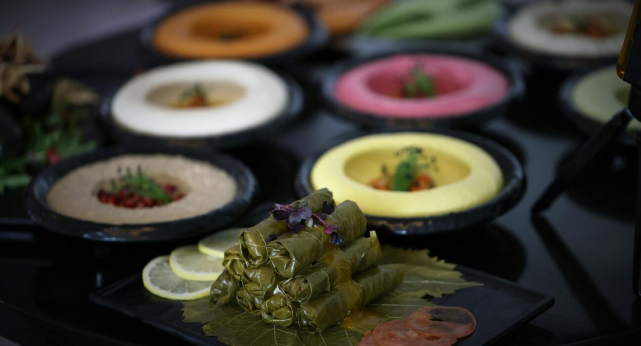 A colorful display of various hummus flavors and dolma on a table, ideal for food photography.