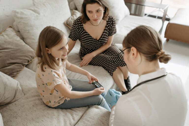 A healthcare provider assists a child with a diabetes check-up at home.