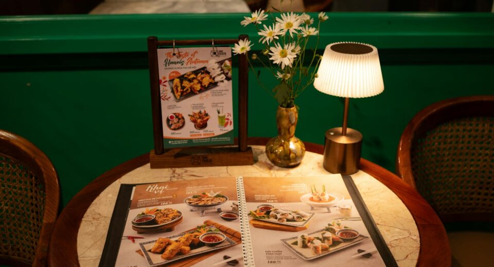 Warm ambiance at restaurant table with menu, flowers, and soft lighting.