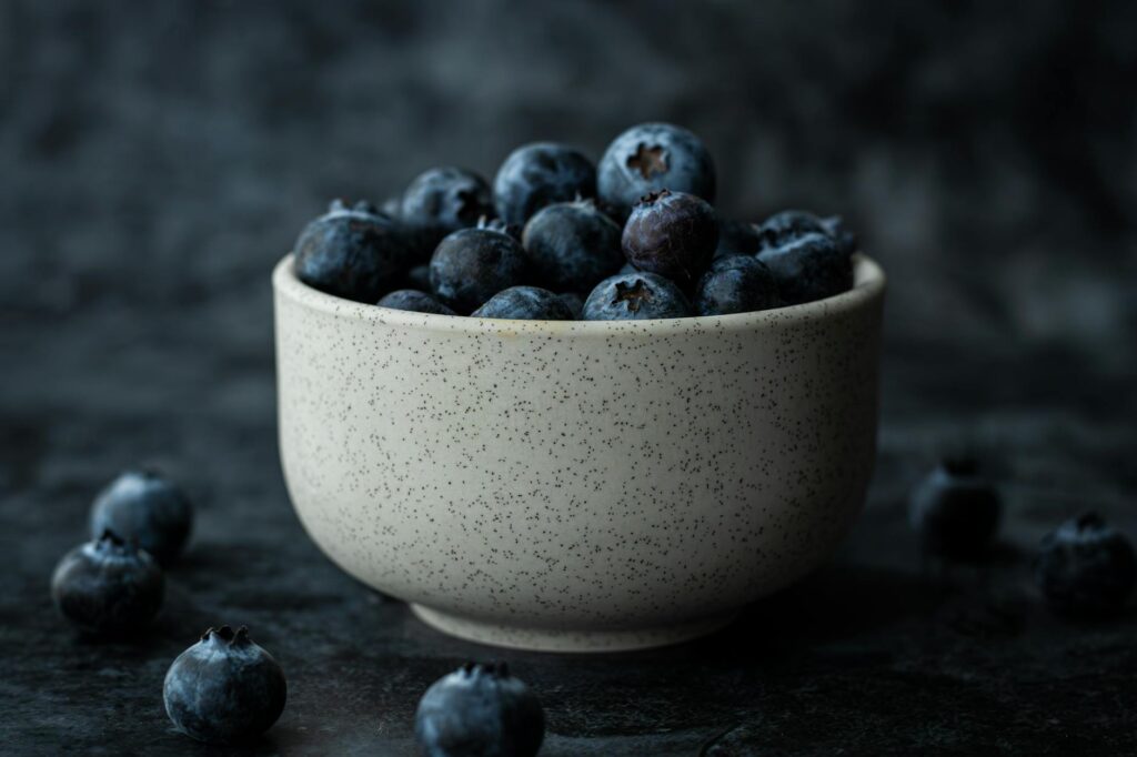 A bowl of ripe blueberries against a dark backdrop, highlighting their freshness and rich color.