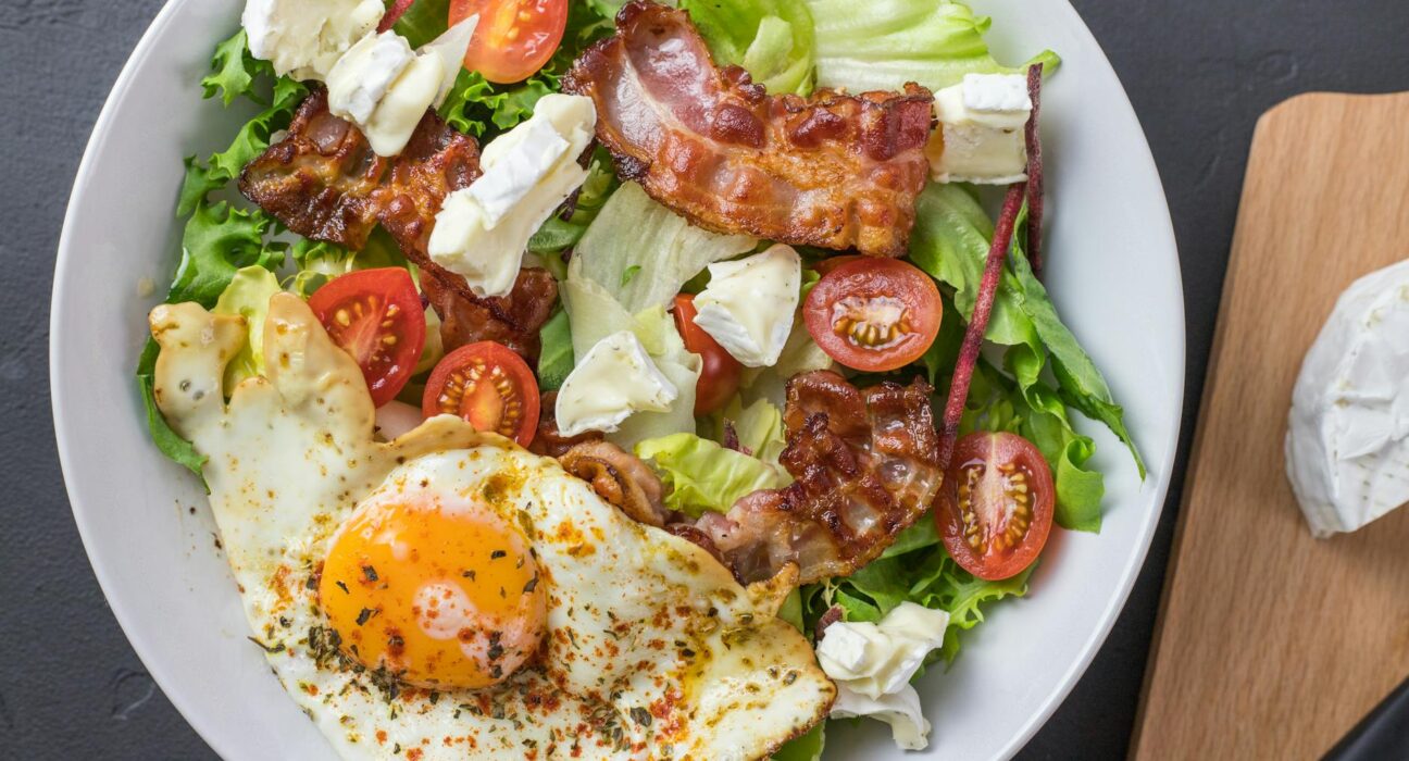 Fresh ketogenic salad with bacon, egg, feta, and tomatoes, perfect for healthy eating.