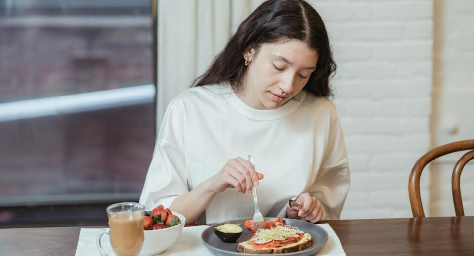 Woman having a nutritious breakfast with toast and strawberries in a cozy indoor setting.