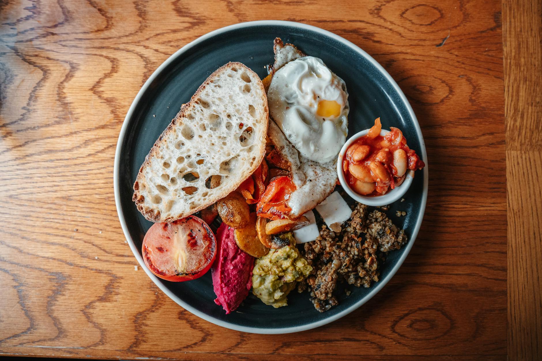 A hearty Scottish breakfast featuring eggs, sausage, beans, and bread on a wooden table.