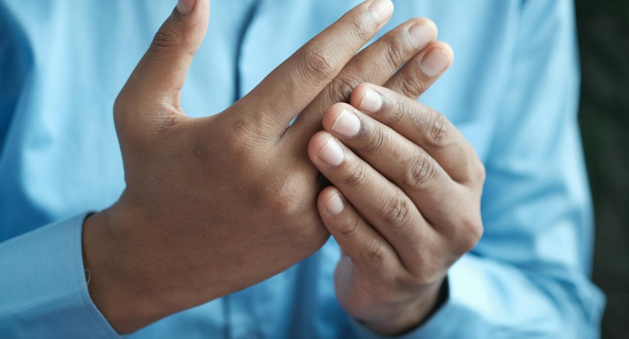Close-up of a man gently holding his hand, symbolizing comfort or pain relief.