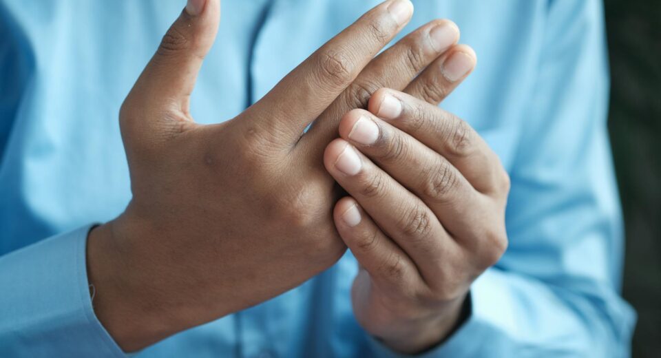 Close-up of a man gently holding his hand, symbolizing comfort or pain relief.