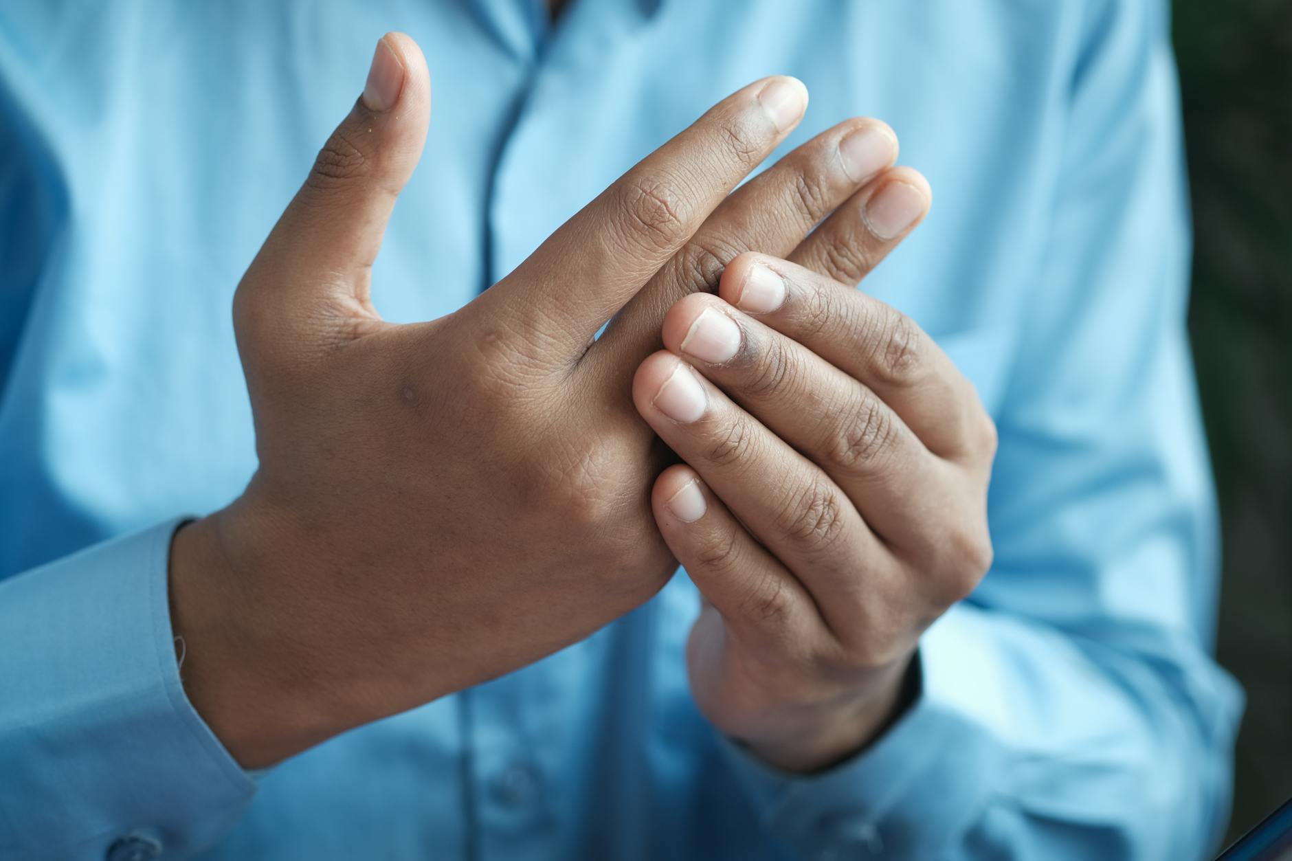 Close-up of a man gently holding his hand, symbolizing comfort or pain relief.