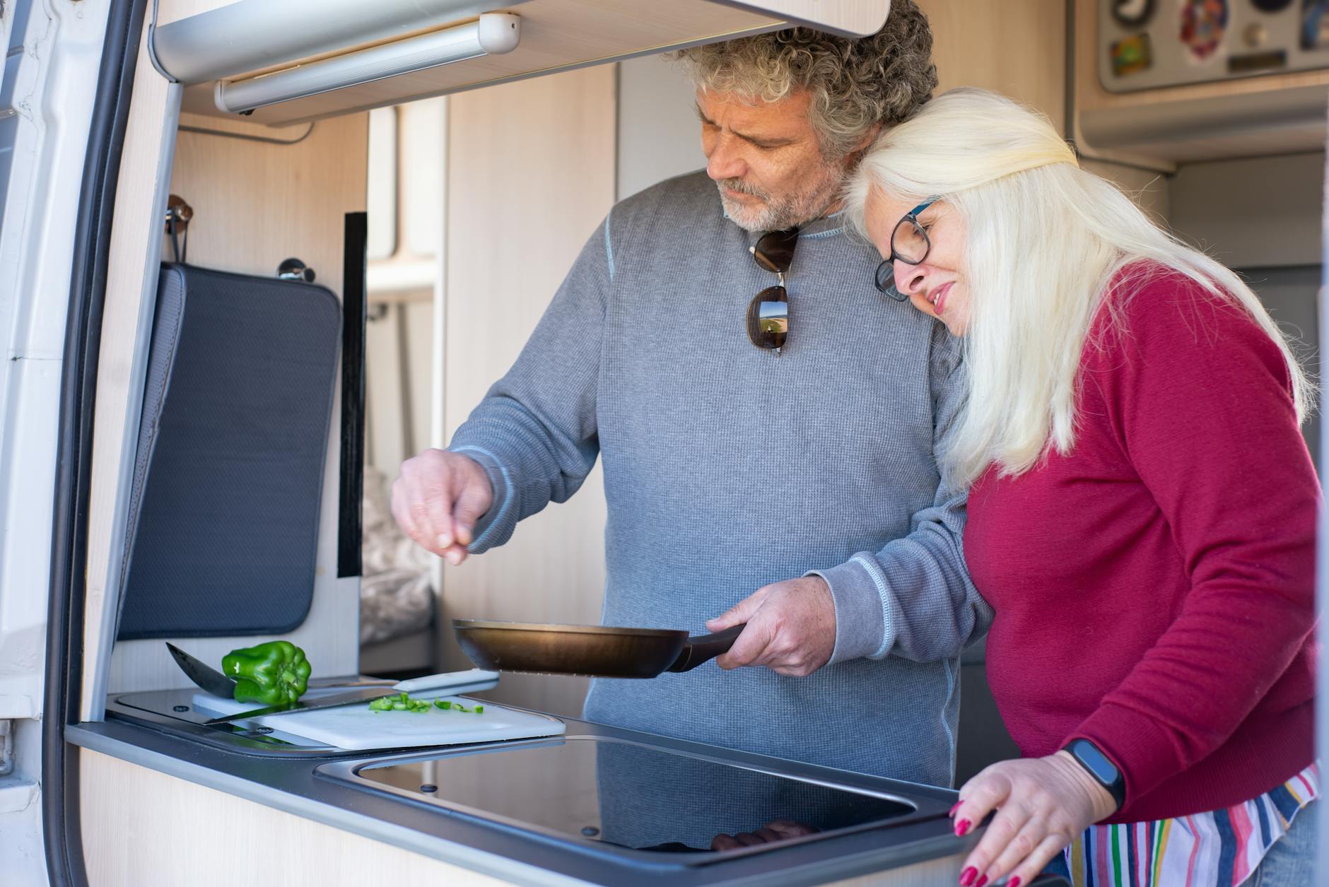 Senior couple cooking together in a motorhome kitchen during a travel trip in Portugal.