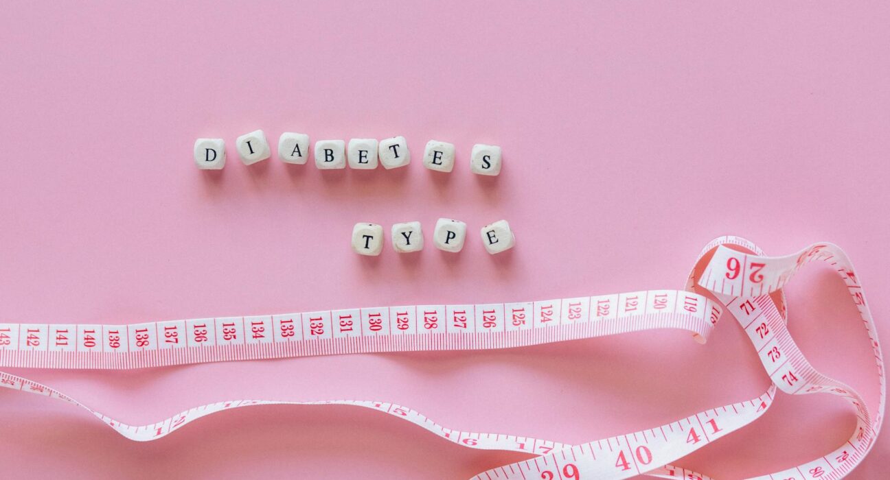 Close-up of diabetes type block letters and measuring tape on pink background.