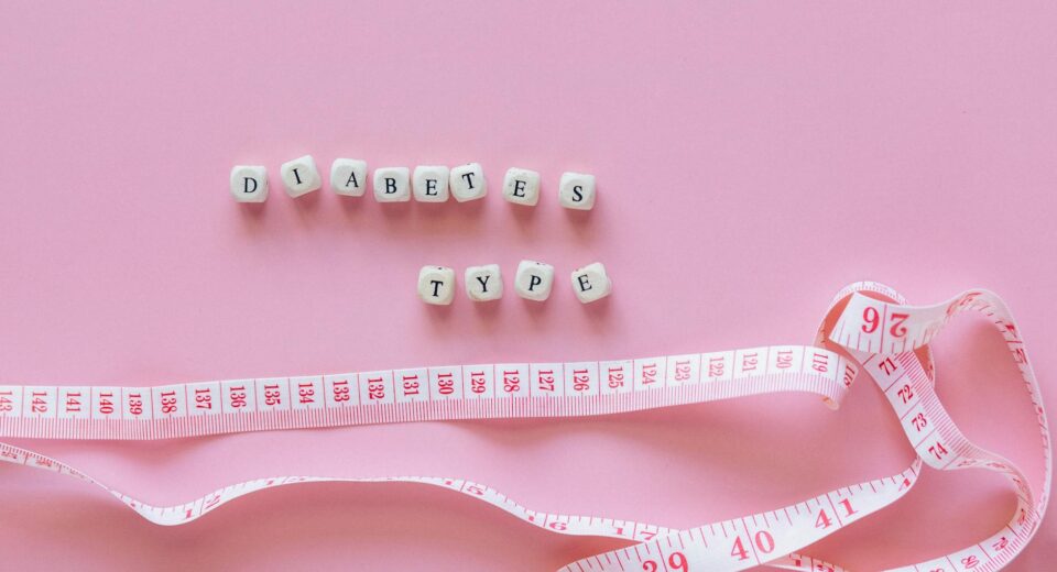Close-up of diabetes type block letters and measuring tape on pink background.