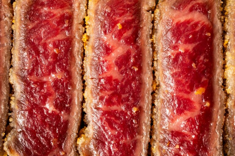 Detailed close-up of raw beef cutlet with a crispy coating texture.