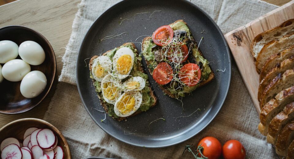 Delicious avocado toast topped with eggs and vegetables, perfect for a healthy breakfast.
