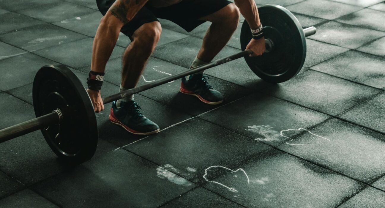 A muscular man in a gym preparing to lift a heavy barbell, showcasing strength and fitness.