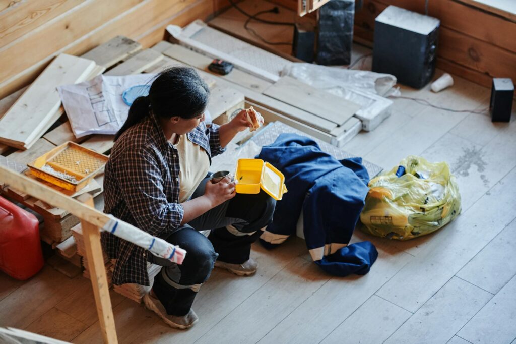 A female construction worker taking a lunch break in a house under renovation, viewed from above.