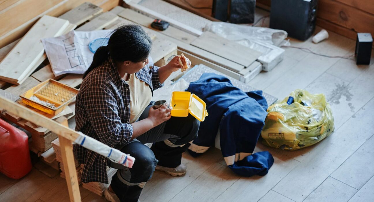A female construction worker taking a lunch break in a house under renovation, viewed from above.