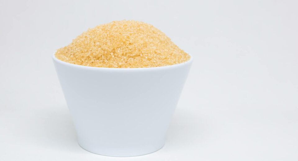 A white bowl filled with brown sugar against a clean, white background.