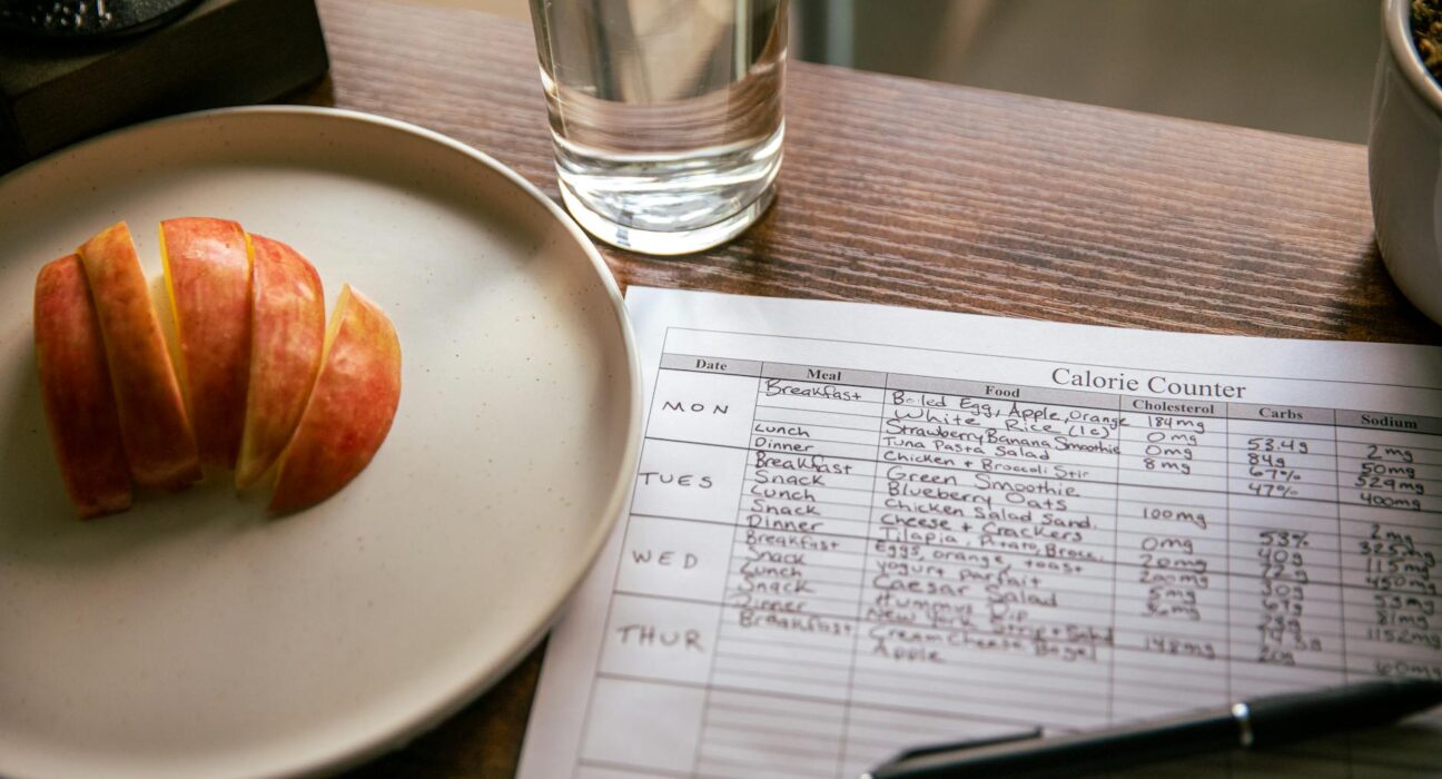A table setup with apple slices, a calorie counting sheet, and a glass of water for a dieting scene.