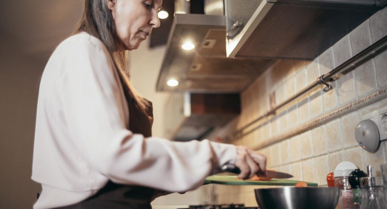 Senior woman preparing a meal in a modern home kitchen, focusing on healthy cooking.