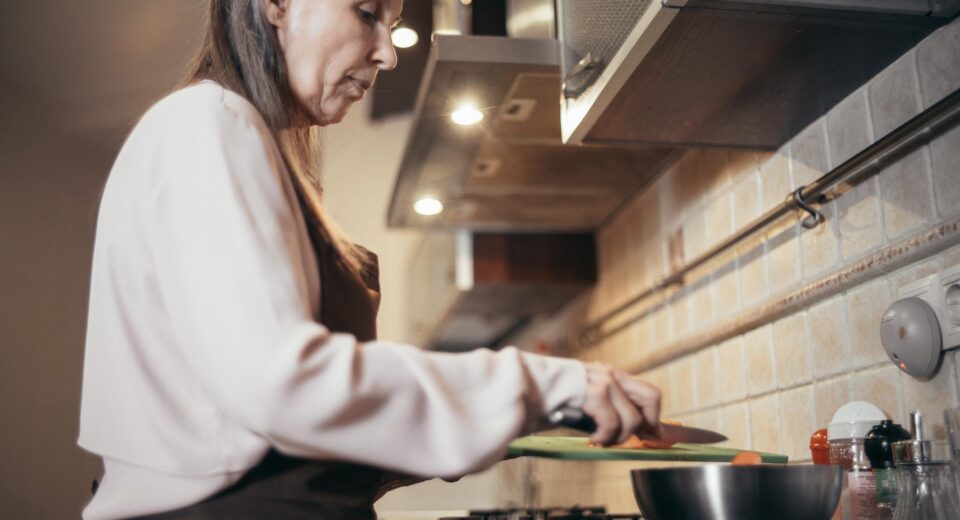 Senior woman preparing a meal in a modern home kitchen, focusing on healthy cooking.