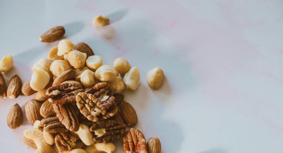 A close-up of various nuts like almonds, pecans, and macadamia on white.