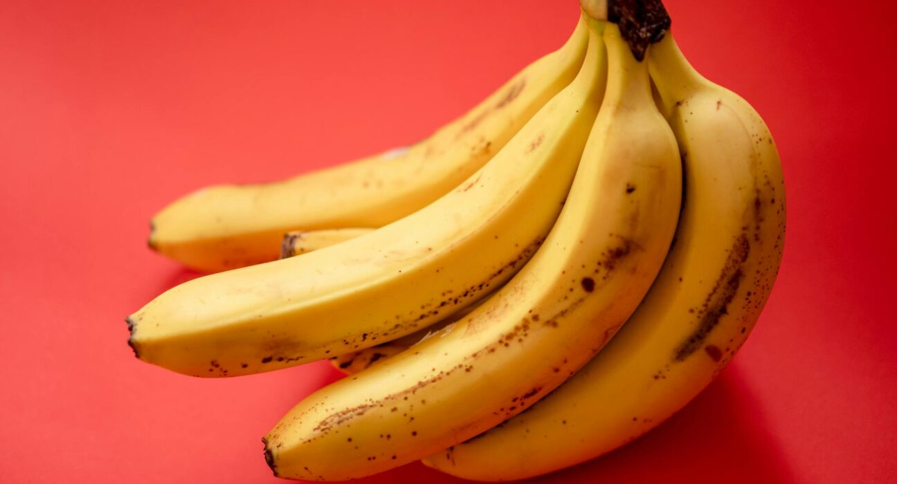 Fresh ripe bananas displayed against a vibrant red background.