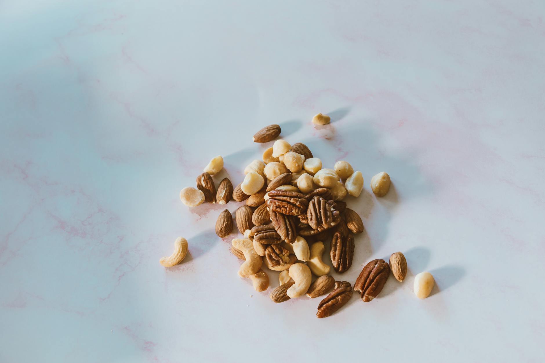 Close-up of assorted nuts on a marble surface, with natural lighting and texture.