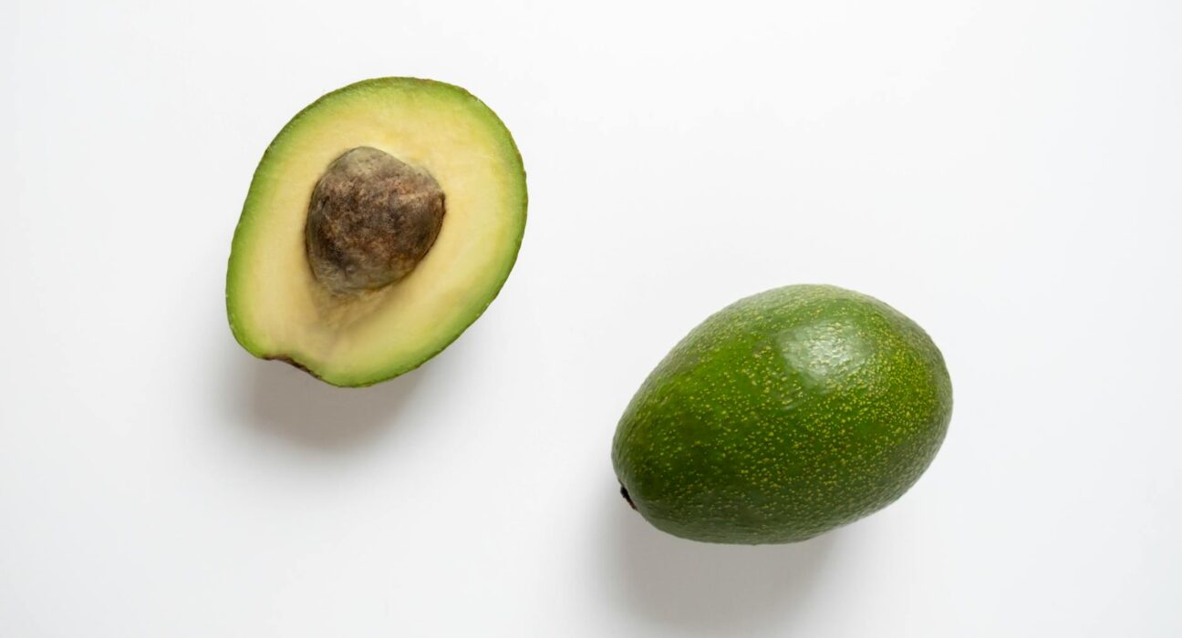 Close-up of a fresh halved avocado with a white background, showing rich texture.