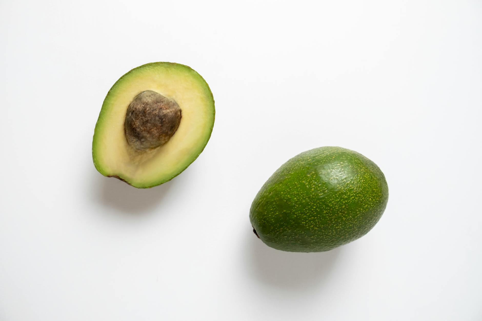 Close-up of a fresh halved avocado with a white background, showing rich texture.