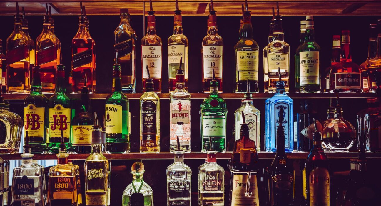 An array of various liquor bottles beautifully displayed on a bar shelf.