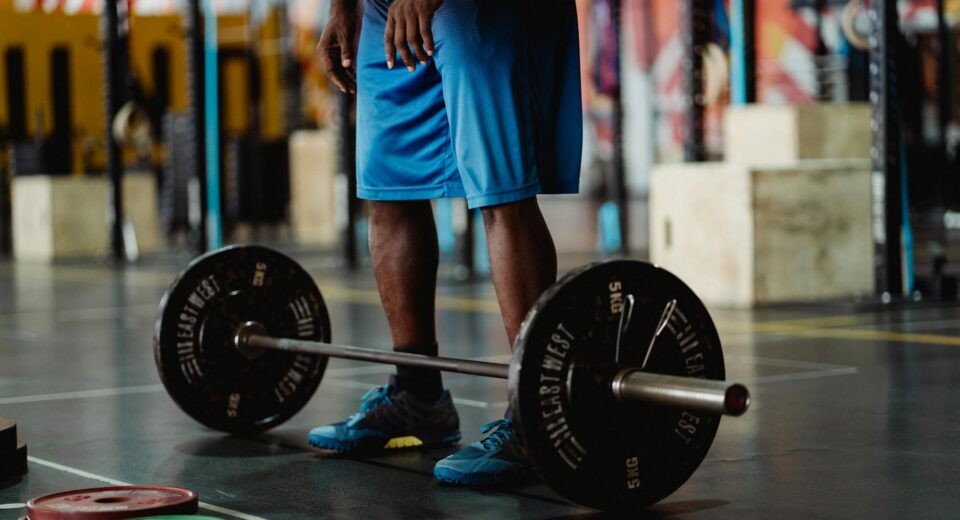 Man preparing for a weightlifting session with barbell and weights in a modern gym.