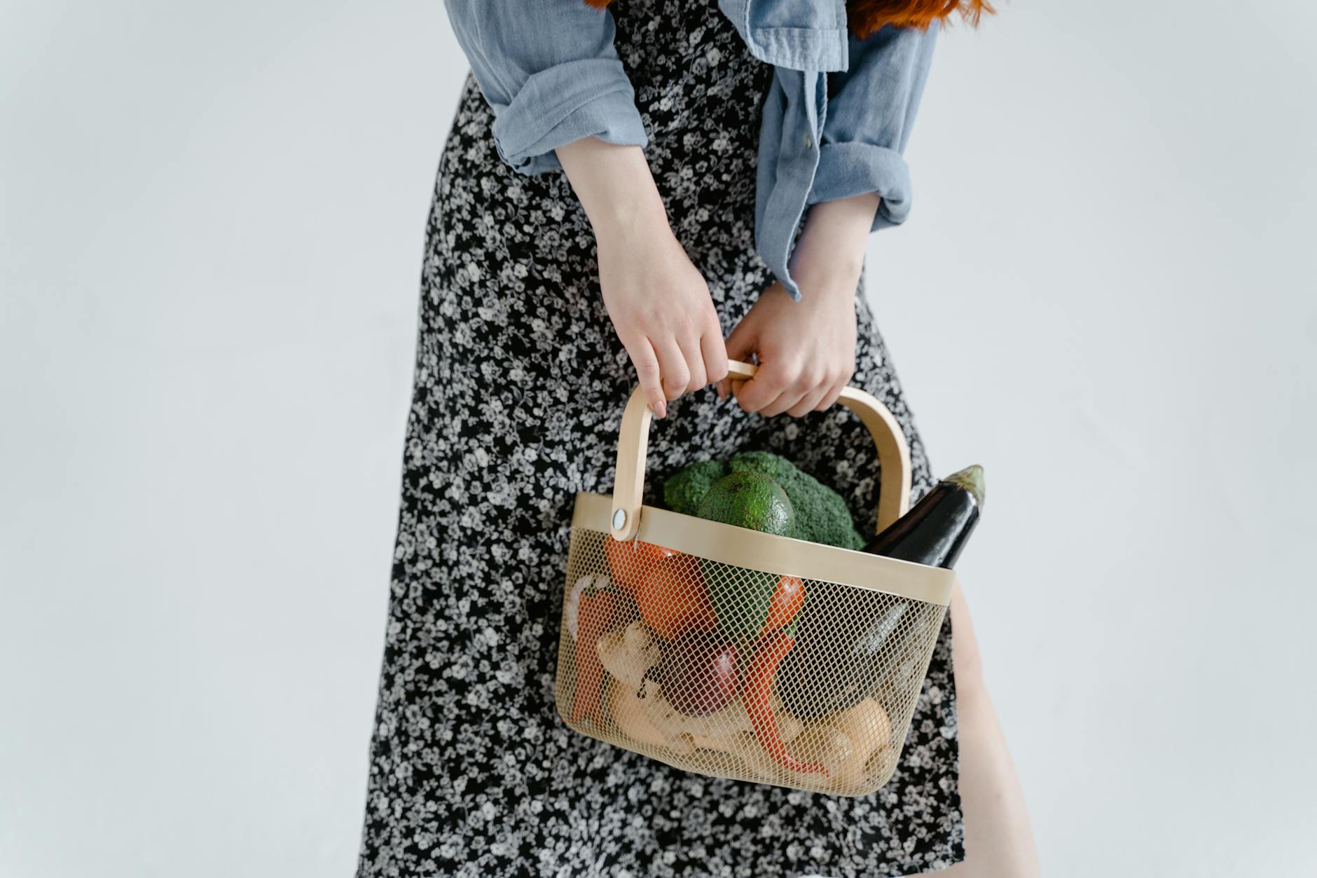 Close-up of a woman holding a basket filled with fresh vegetables, emphasizing healthy and organic lifestyle.