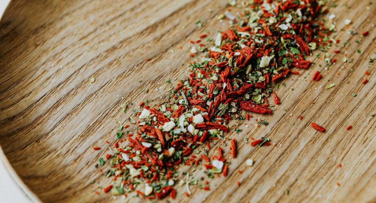 Close-up of vibrant dried herbs and spices scattered on a wooden board.