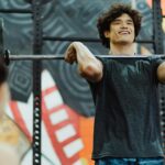 Young Asian man lifting a barbell indoors, showcasing strength and determination.